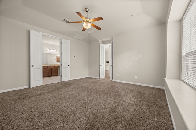 unfurnished bedroom featuring lofted ceiling, ensuite bath, ceiling fan, and carpet