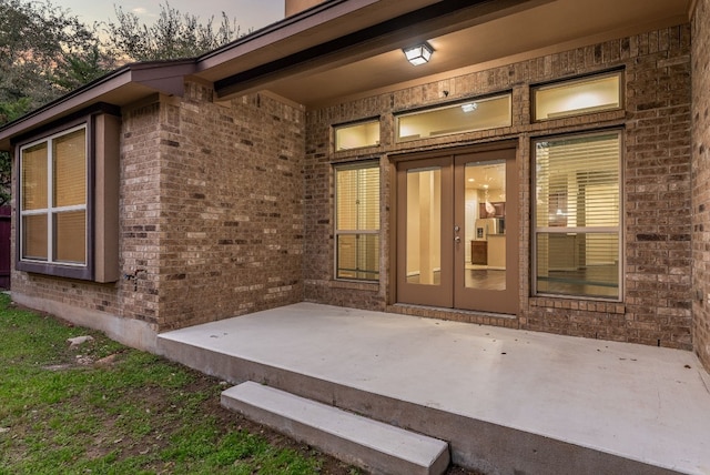 exterior entry at dusk featuring a patio and french doors