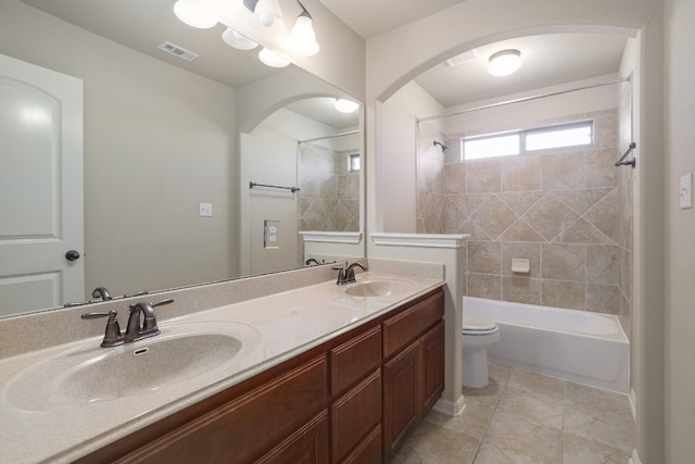 full bathroom featuring vanity, tiled shower / bath, and toilet