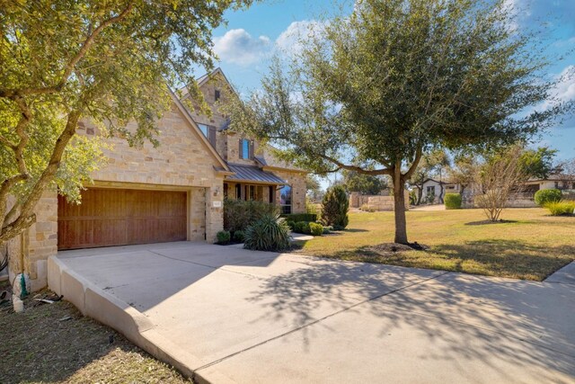 5025 Patagonia Pass, Austin, TX 78738 - view of side of home featuring concrete driveway, stone siding, a garage, a standing seam roof, and a lawn