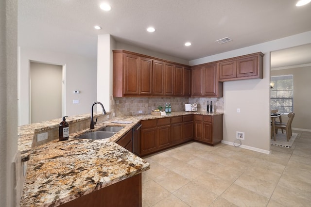 kitchen with light stone counters, kitchen peninsula, sink, and tasteful backsplash