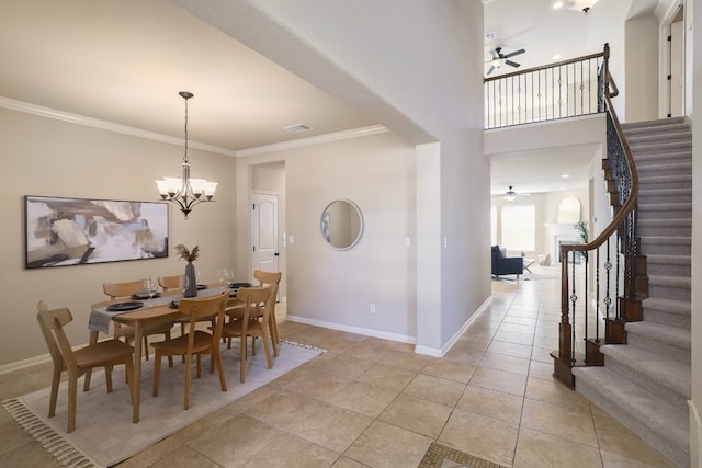 dining room with a towering ceiling, ornamental molding, ceiling fan with notable chandelier, and light tile patterned floors