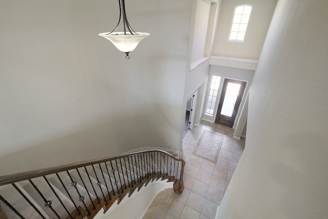 stairs featuring a towering ceiling and tile patterned flooring