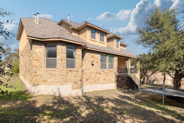 5025 Patagonia Pass, Austin, TX 78738 - back of property with a trampoline, stone siding, stairway, and a shingled roof