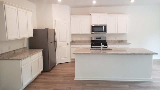 kitchen featuring stainless steel appliances, a center island with sink, and white cabinets