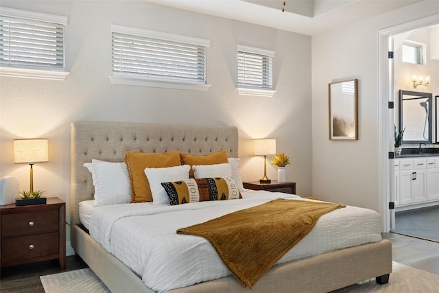 bedroom with ensuite bathroom, sink, and hardwood / wood-style floors