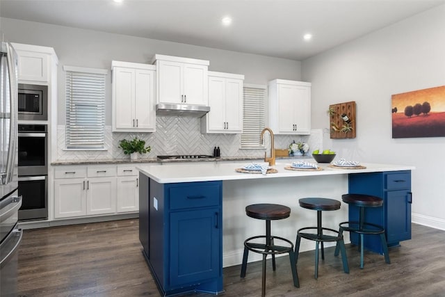 kitchen with a kitchen bar, dark hardwood / wood-style flooring, an island with sink, and white cabinets