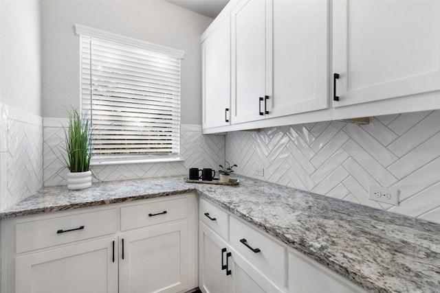 kitchen with tasteful backsplash, white cabinetry, and light stone counters