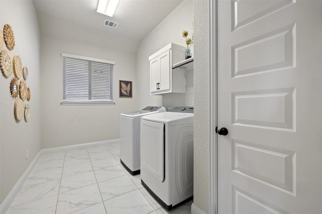 clothes washing area featuring cabinets and washing machine and dryer