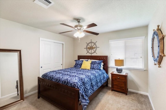 carpeted bedroom featuring ceiling fan, a textured ceiling, and a closet