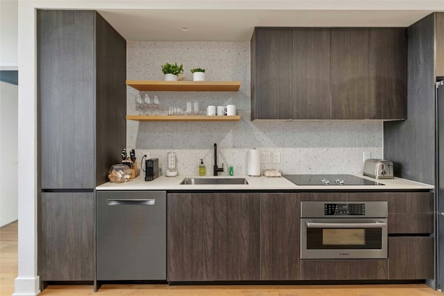 kitchen with stainless steel appliances, dark brown cabinets, sink, and light hardwood / wood-style flooring