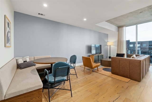 interior space with a wall of windows and light hardwood / wood-style flooring