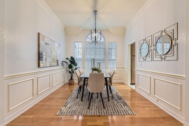 dining space featuring crown molding, a decorative wall, and light wood-style floors