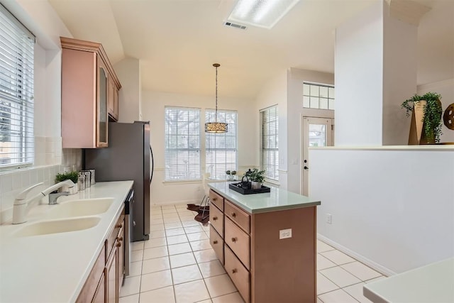 kitchen featuring a wealth of natural light, light countertops, backsplash, a kitchen island, and a sink