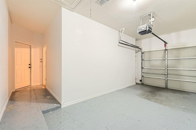 garage featuring a garage door opener, visible vents, and baseboards