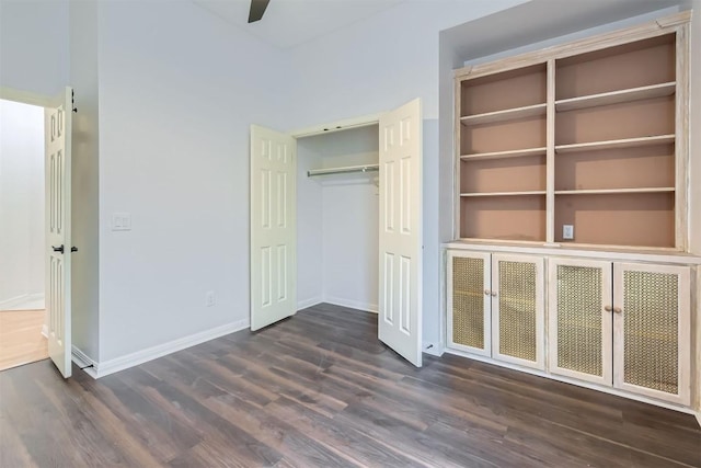 unfurnished bedroom with a ceiling fan, baseboards, dark wood finished floors, and a closet