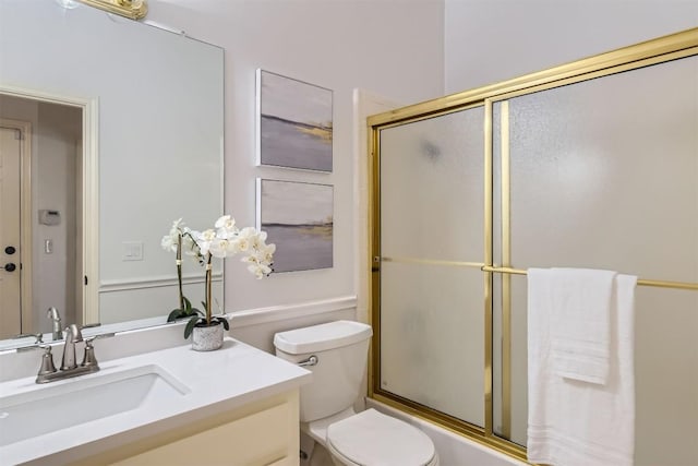 bathroom featuring toilet, shower / bath combination with glass door, and vanity