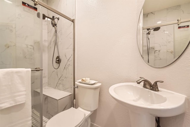 full bathroom with toilet, a marble finish shower, a sink, and a textured wall