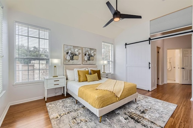 bedroom with a barn door, baseboards, a ceiling fan, lofted ceiling, and wood finished floors