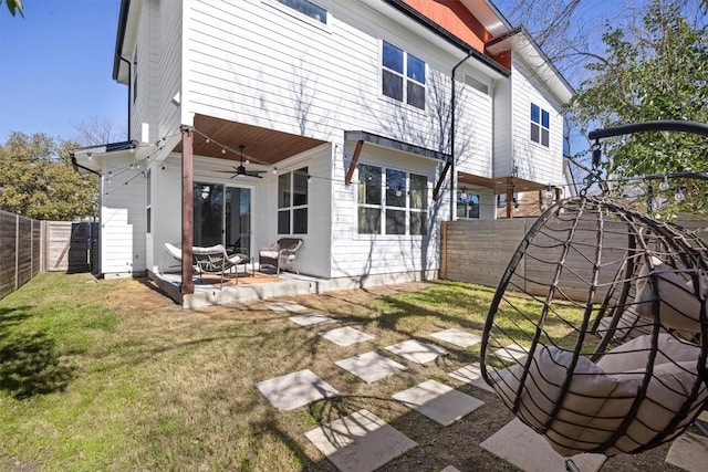 rear view of house with ceiling fan, a patio area, and a lawn