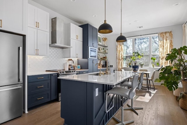 kitchen featuring white cabinetry, a breakfast bar area, wall chimney exhaust hood, and appliances with stainless steel finishes