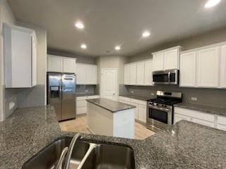 kitchen featuring appliances with stainless steel finishes, a center island, dark stone countertops, and white cabinets