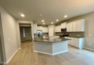 kitchen featuring stainless steel appliances, tasteful backsplash, white cabinets, and light hardwood / wood-style flooring