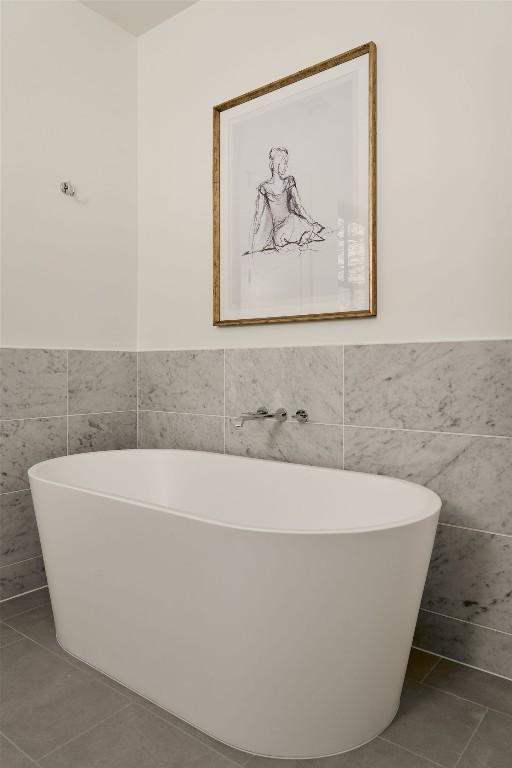 bathroom with tile patterned flooring, a tub, and tile walls