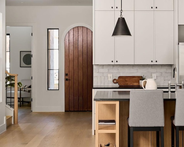 kitchen featuring tasteful backsplash, white cabinetry, a breakfast bar area, and light hardwood / wood-style flooring