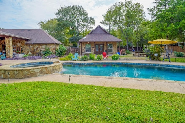 view of pool with an in ground hot tub, a yard, an outdoor structure, and a patio area