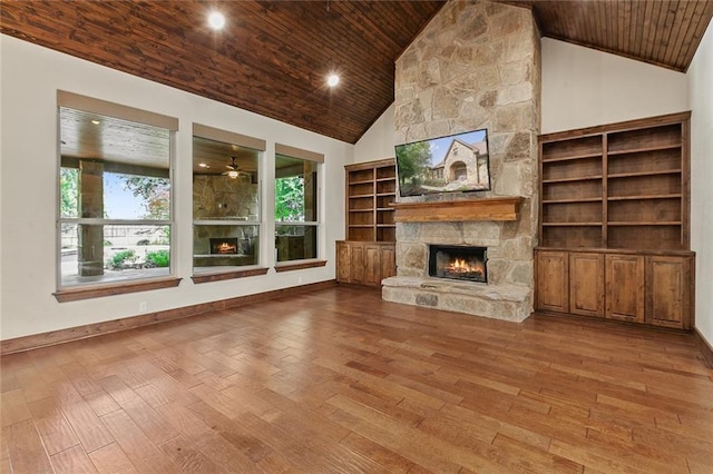 unfurnished living room with hardwood / wood-style flooring, a stone fireplace, and wooden ceiling