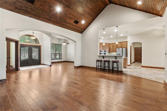 foyer entrance with french doors, wood ceiling, high vaulted ceiling, light wood-type flooring, and ceiling fan