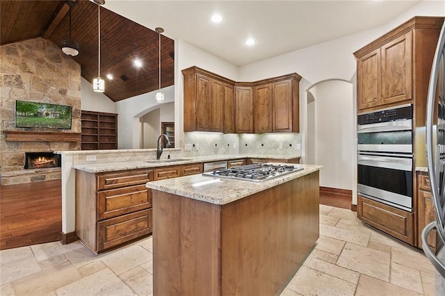 kitchen featuring sink, wood ceiling, hanging light fixtures, a kitchen island, and light stone countertops