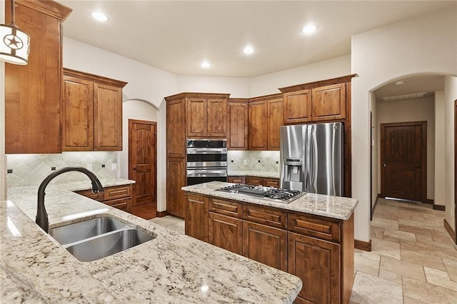 kitchen featuring hanging light fixtures, a center island, light stone countertops, sink, and appliances with stainless steel finishes