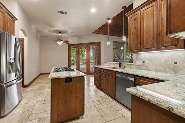 kitchen featuring appliances with stainless steel finishes, sink, backsplash, hanging light fixtures, and a center island