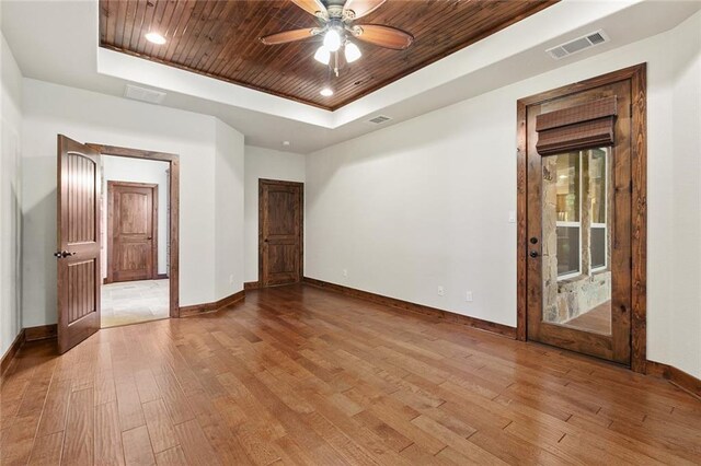 unfurnished room featuring light hardwood / wood-style flooring, wooden ceiling, ceiling fan, and a tray ceiling