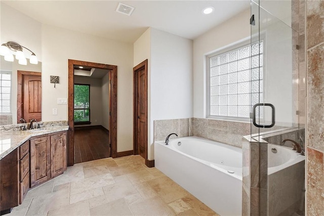 bathroom with a healthy amount of sunlight, a bathtub, and vanity