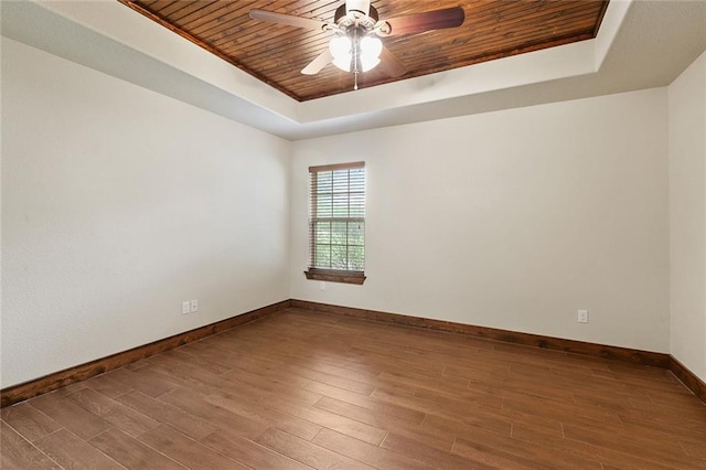 empty room with wood ceiling, ceiling fan, a tray ceiling, and hardwood / wood-style flooring