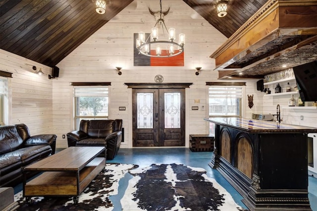 living room with french doors, wooden ceiling, high vaulted ceiling, wooden walls, and a chandelier