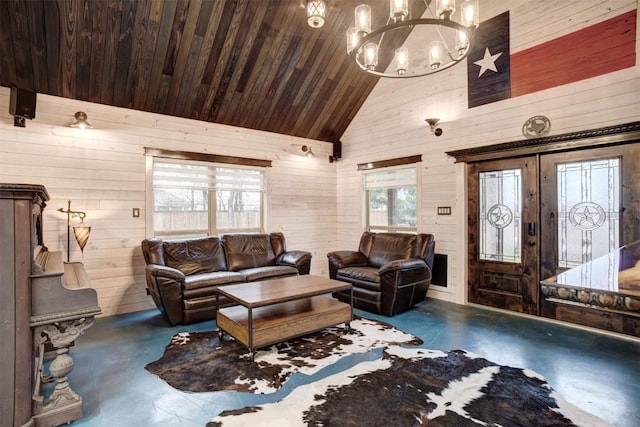 living room with a notable chandelier, high vaulted ceiling, concrete flooring, and wooden walls