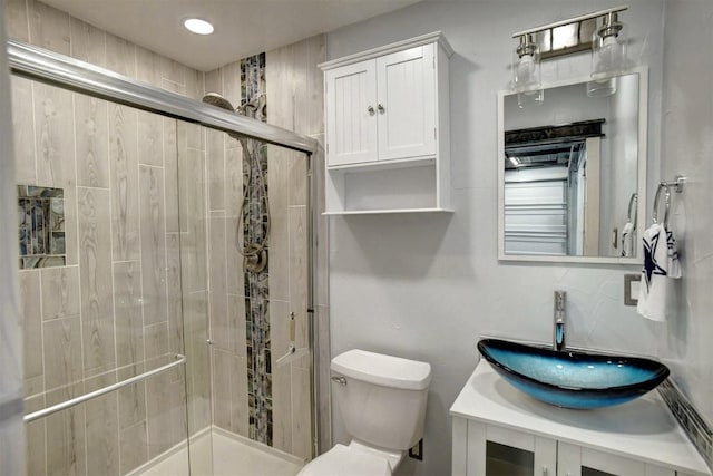 bathroom with toilet, vanity, and a shower with shower door