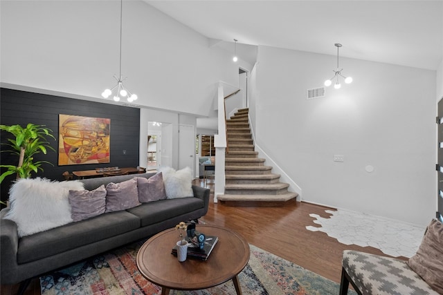 living room with hardwood / wood-style flooring, a notable chandelier, and high vaulted ceiling