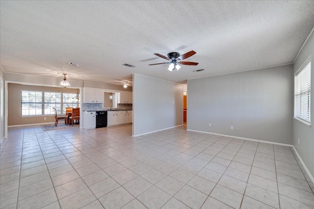 unfurnished living room with plenty of natural light, ceiling fan with notable chandelier, a textured ceiling, and light tile patterned floors