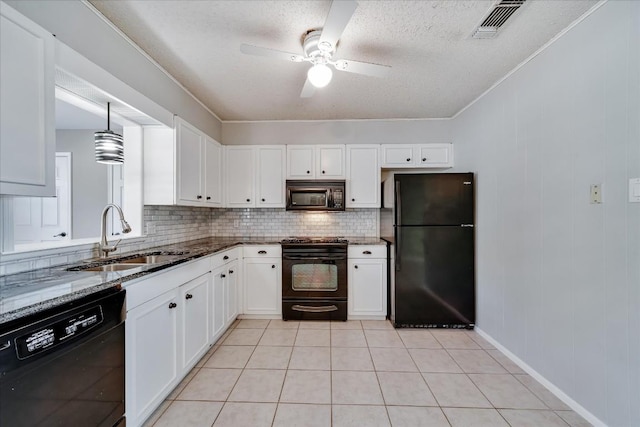 kitchen featuring sink, dark stone countertops, white cabinets, hanging light fixtures, and black appliances