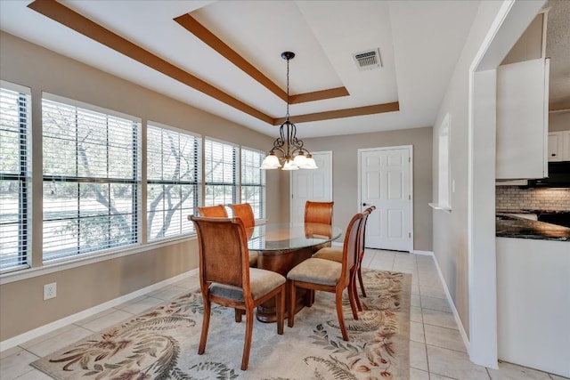 dining room with an inviting chandelier, light tile patterned floors, and a raised ceiling