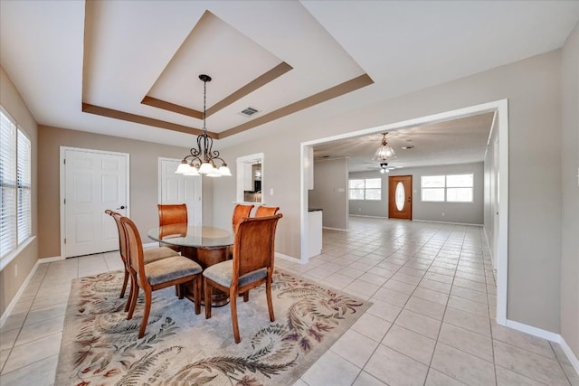 dining area with light tile patterned flooring, a raised ceiling, and ceiling fan with notable chandelier