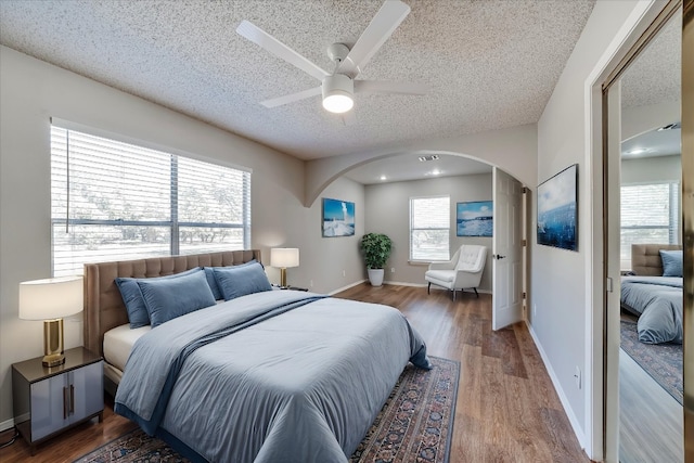 bedroom featuring multiple windows, ceiling fan, hardwood / wood-style floors, and a textured ceiling