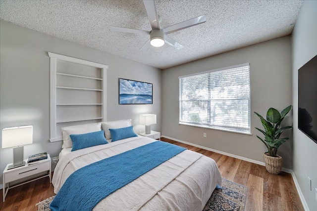 bedroom with ceiling fan, dark hardwood / wood-style floors, and a textured ceiling