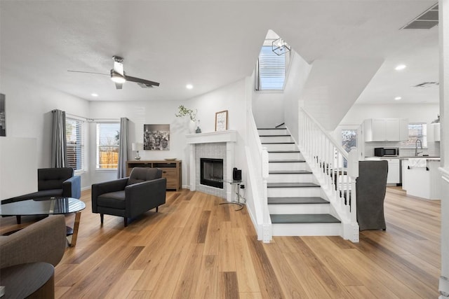 living room with ceiling fan, sink, and light hardwood / wood-style flooring