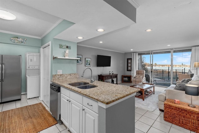 kitchen with sink, crown molding, stainless steel appliances, stacked washer / dryer, and white cabinets